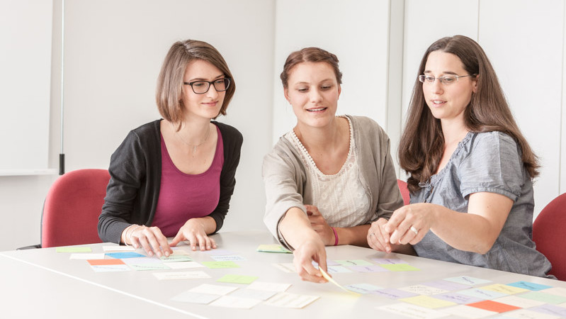 Drei Frauen brainstormen mithilfe von Post-Its